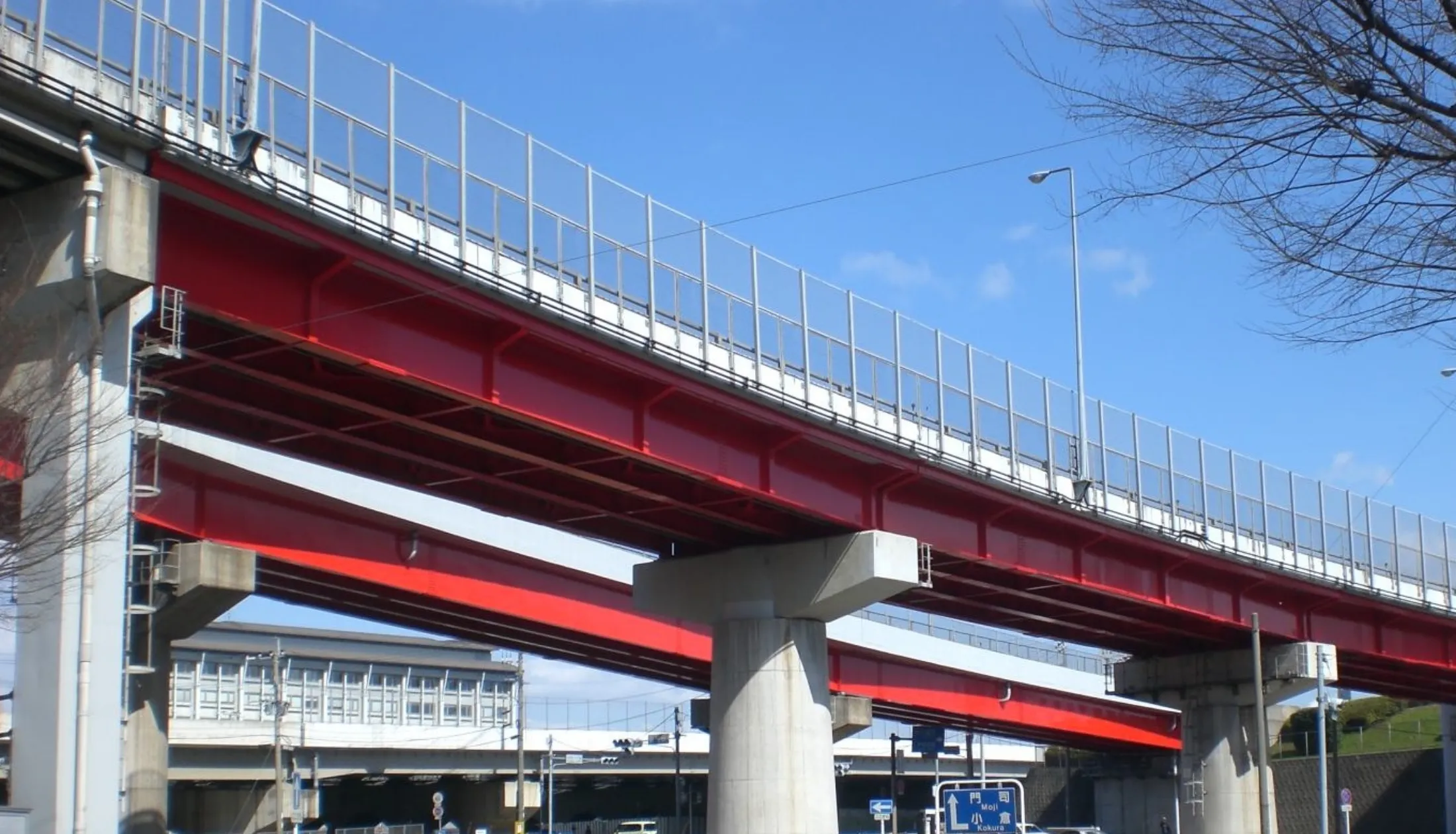 青空の下に映える、鮮やかな赤色の塗装が施された高架道路の橋梁部分