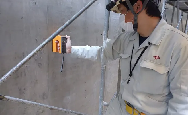 壁に装置を当てている様子